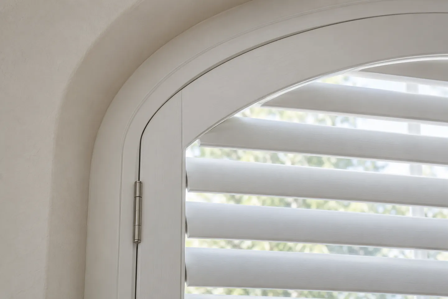 Close view of a curved white shutter frame, hinge and horizontal louvres